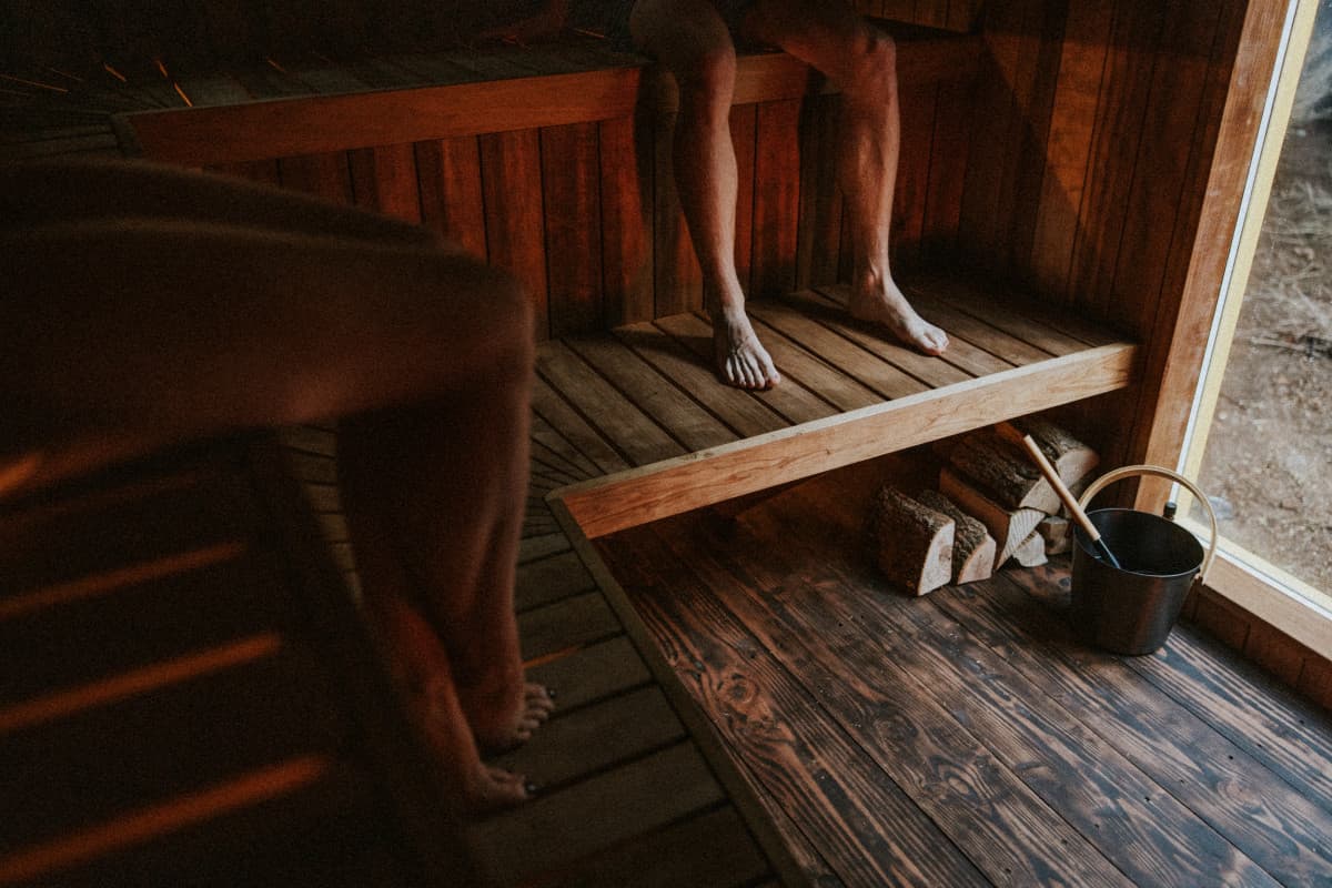 Inside the wood-fired sauna at Campwell Farm with wooden benches and water bucket