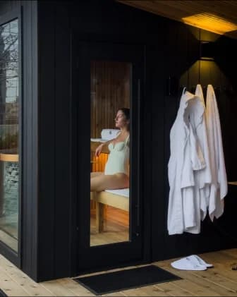 Cedar & Stone black sauna cabin exterior with robes hanging outside on the Four Seasons terrace