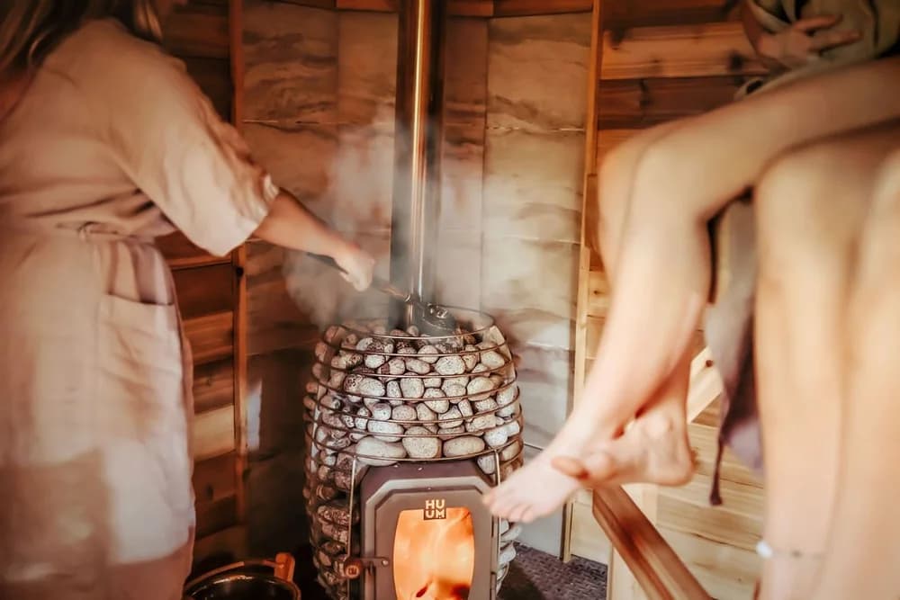 Homestead Saunas wood-fired HUUM stove with steam rising from hot stones