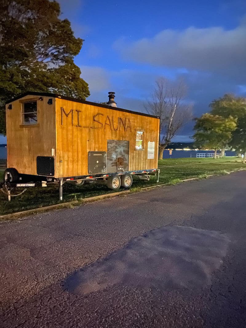 Mi Sauna mobile wood-fired sauna trailer at dusk by the waterfront in Traverse City, Michigan