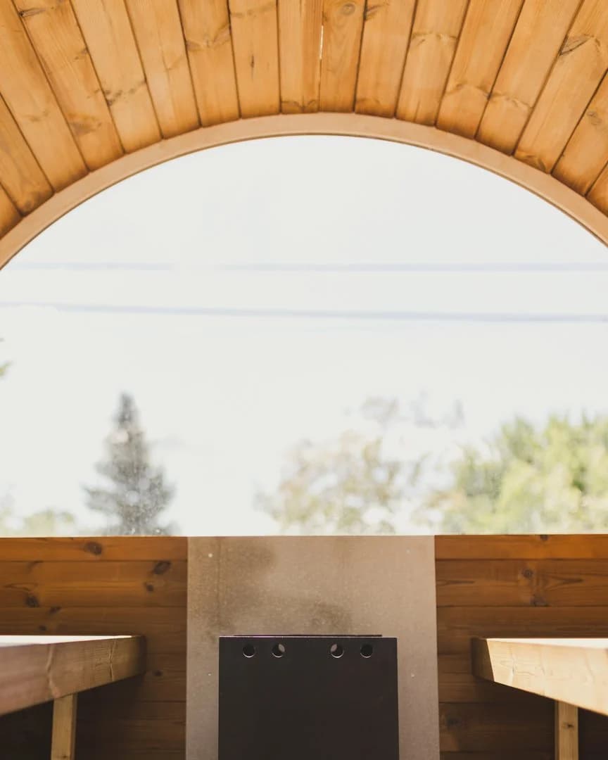 Inside the cedar sauna at Doran Beach with arched window and wood-fired stove