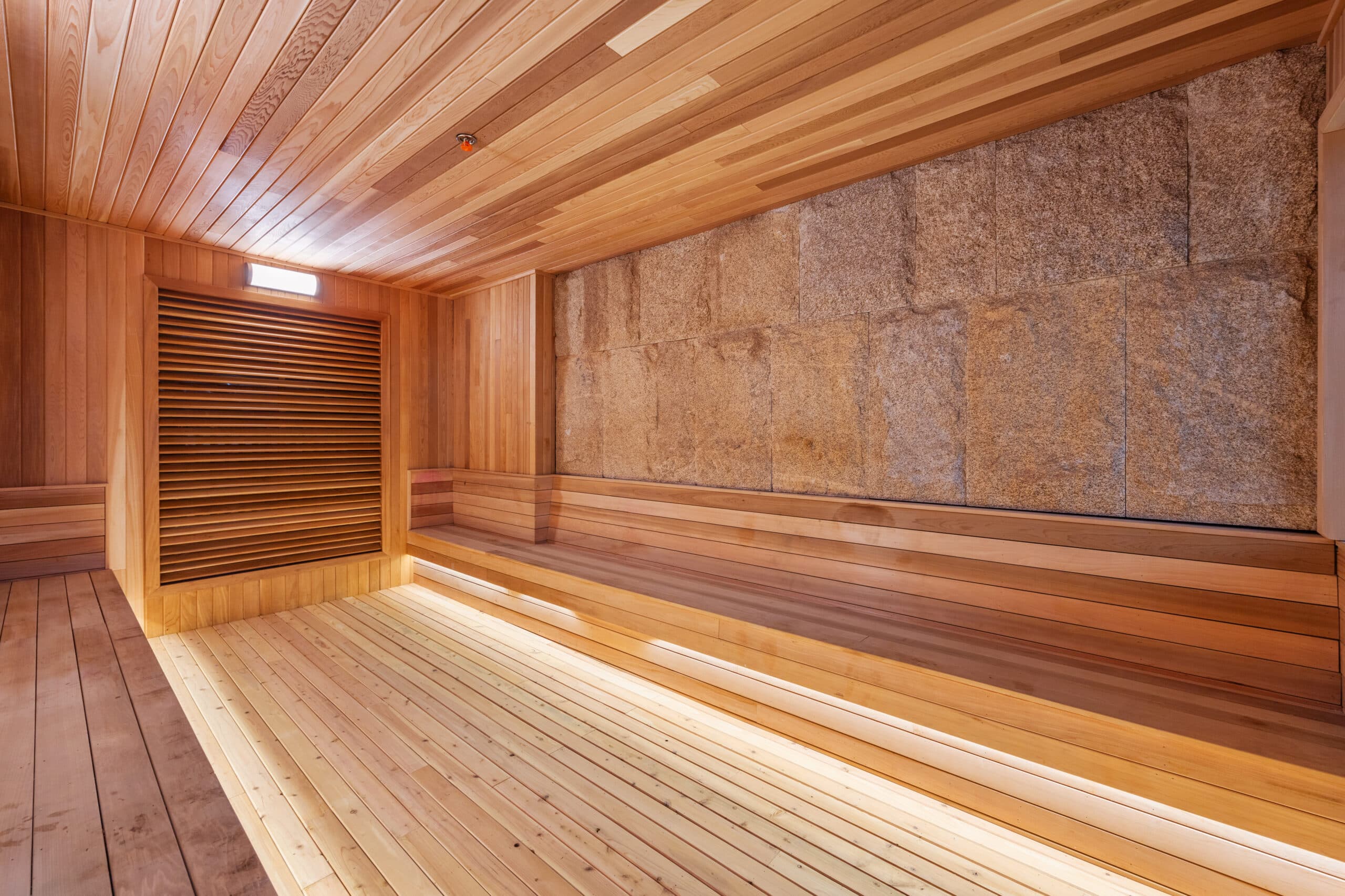 Wood-paneled dry sauna with stone wall at Spa Castle New York