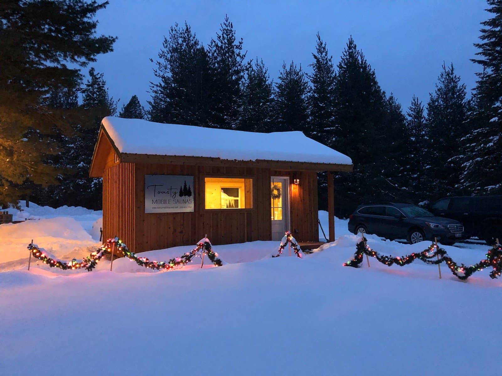Toasty Mobile Saunas wood-fired sauna exterior at dusk in winter with warm light glowing from inside