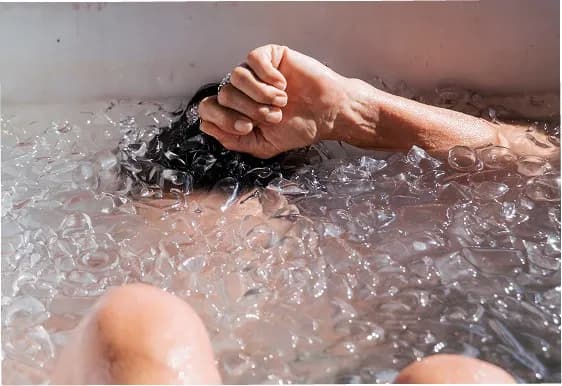 Guest immersed in an ice-filled cold plunge at All's Well Sauna + Waterspa