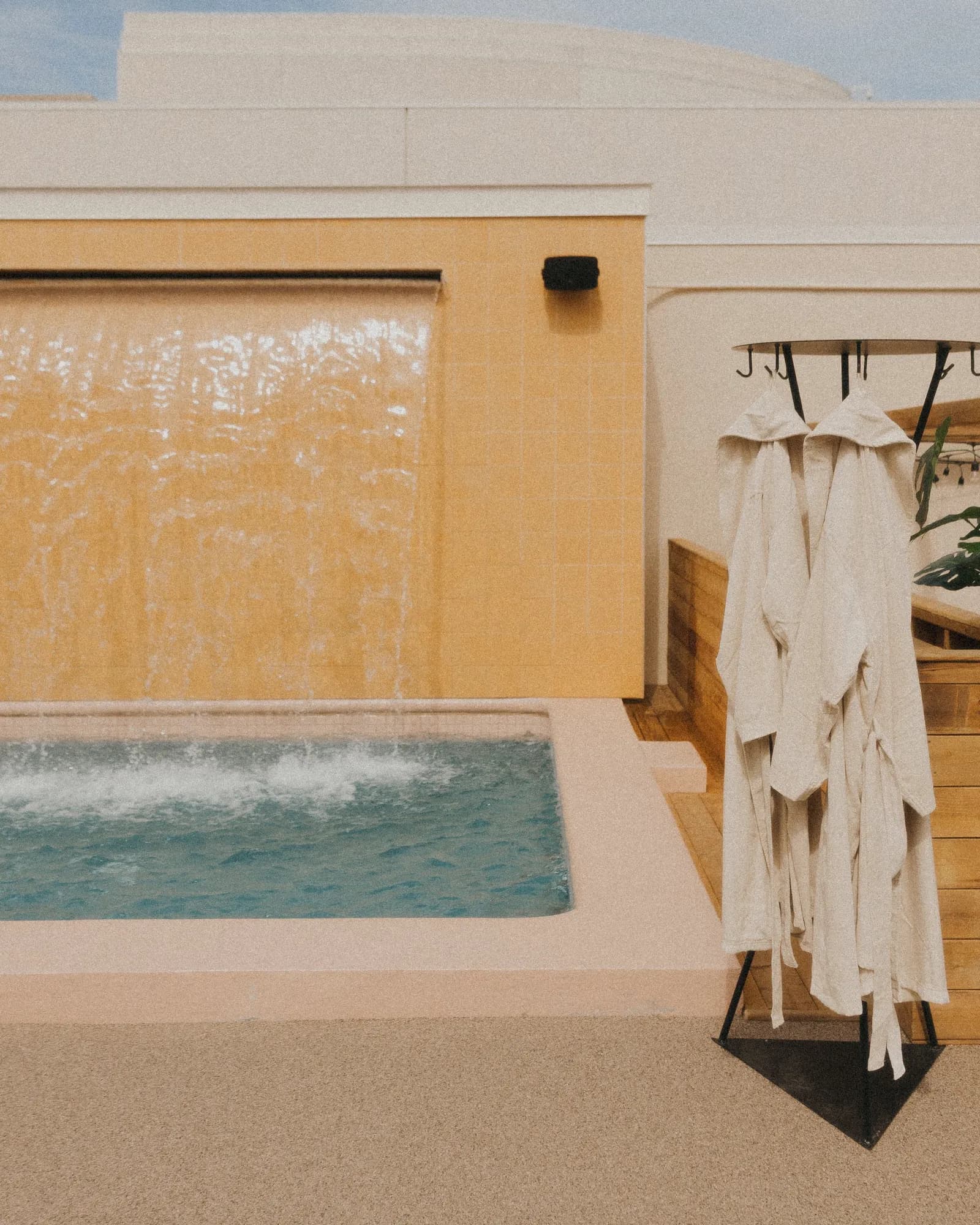 Outdoor cold bath with waterfall and bathrobes on the AWŪ Quartier DIX30 rooftop