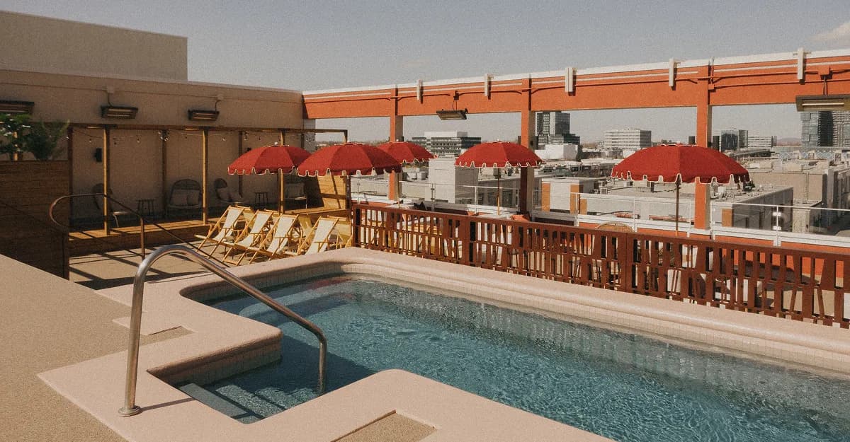 Rooftop hot bath with red umbrellas and city views at AWŪ Quartier DIX30