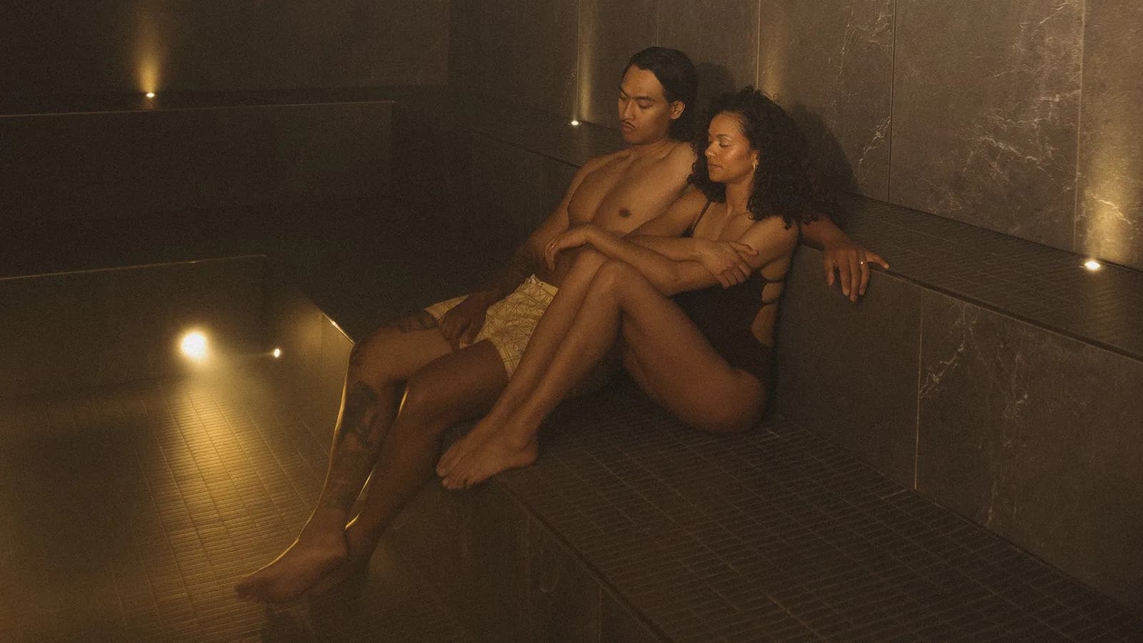 Dim tiled steam bath with guests relaxing at AWŪ Quartier DIX30