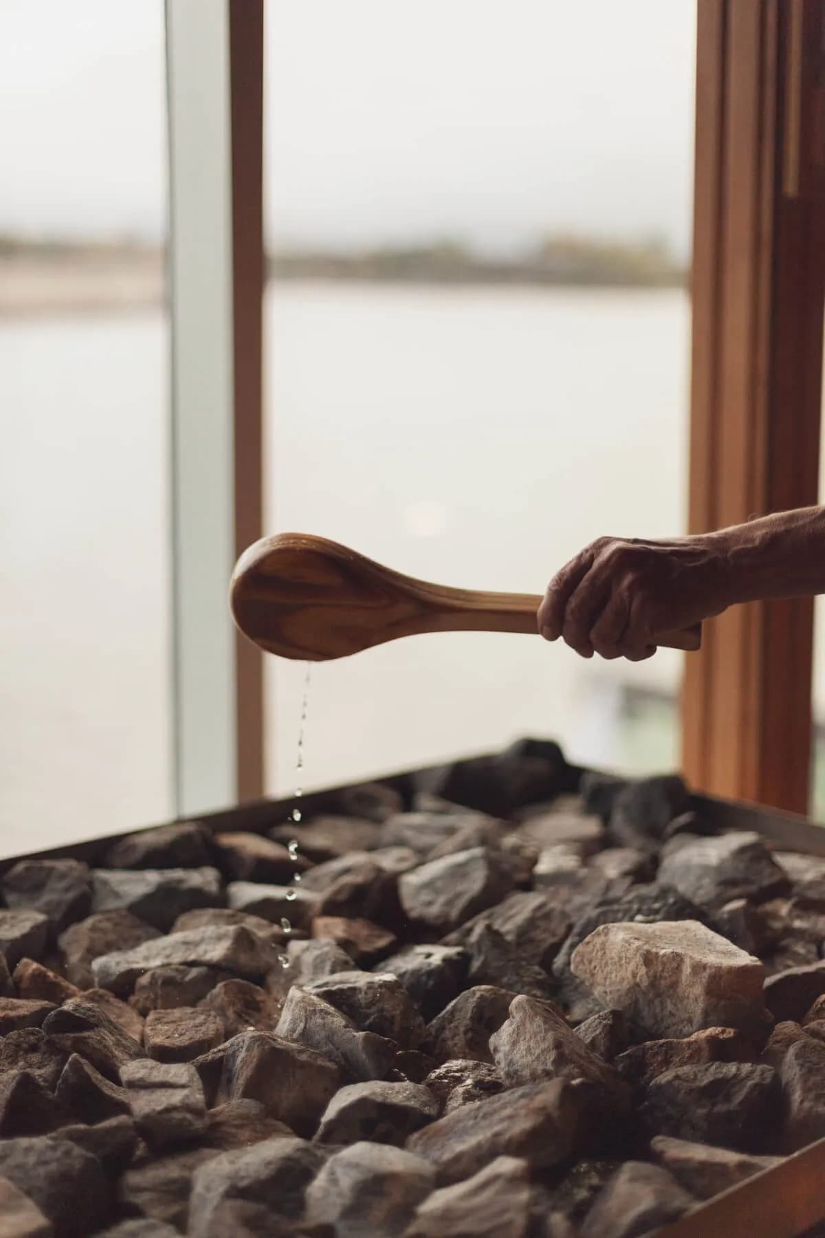 Water being ladled onto sauna rocks with a view of the St. Lawrence River at Bota Bota