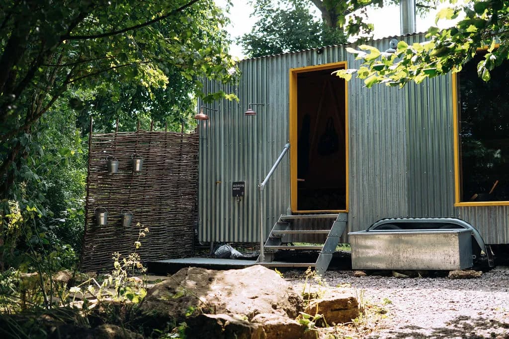 Campwell Farm sauna building exterior with cold plunge trough surrounded by woodland