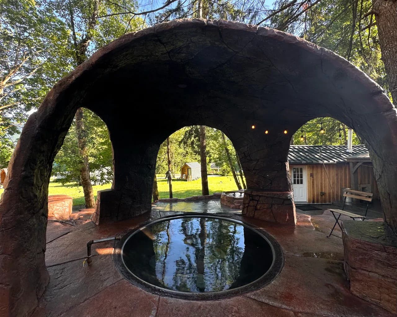 The Cannibal Hot Tub at Paradise Village, a round iron kettle under a stone arch surrounded by trees