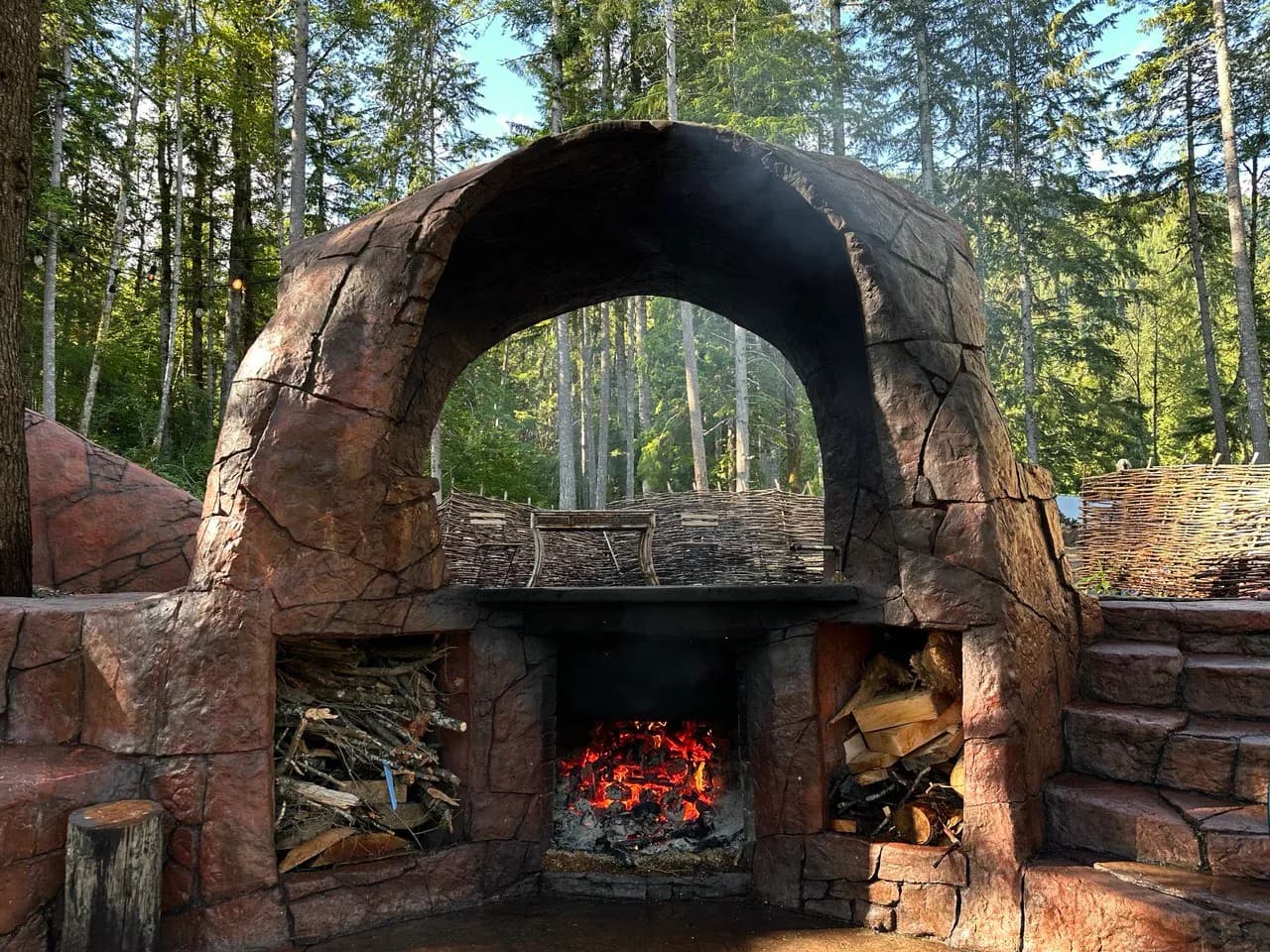 Stone arch fireplace structure of the Cannibal Hot Tub with burning wood beneath