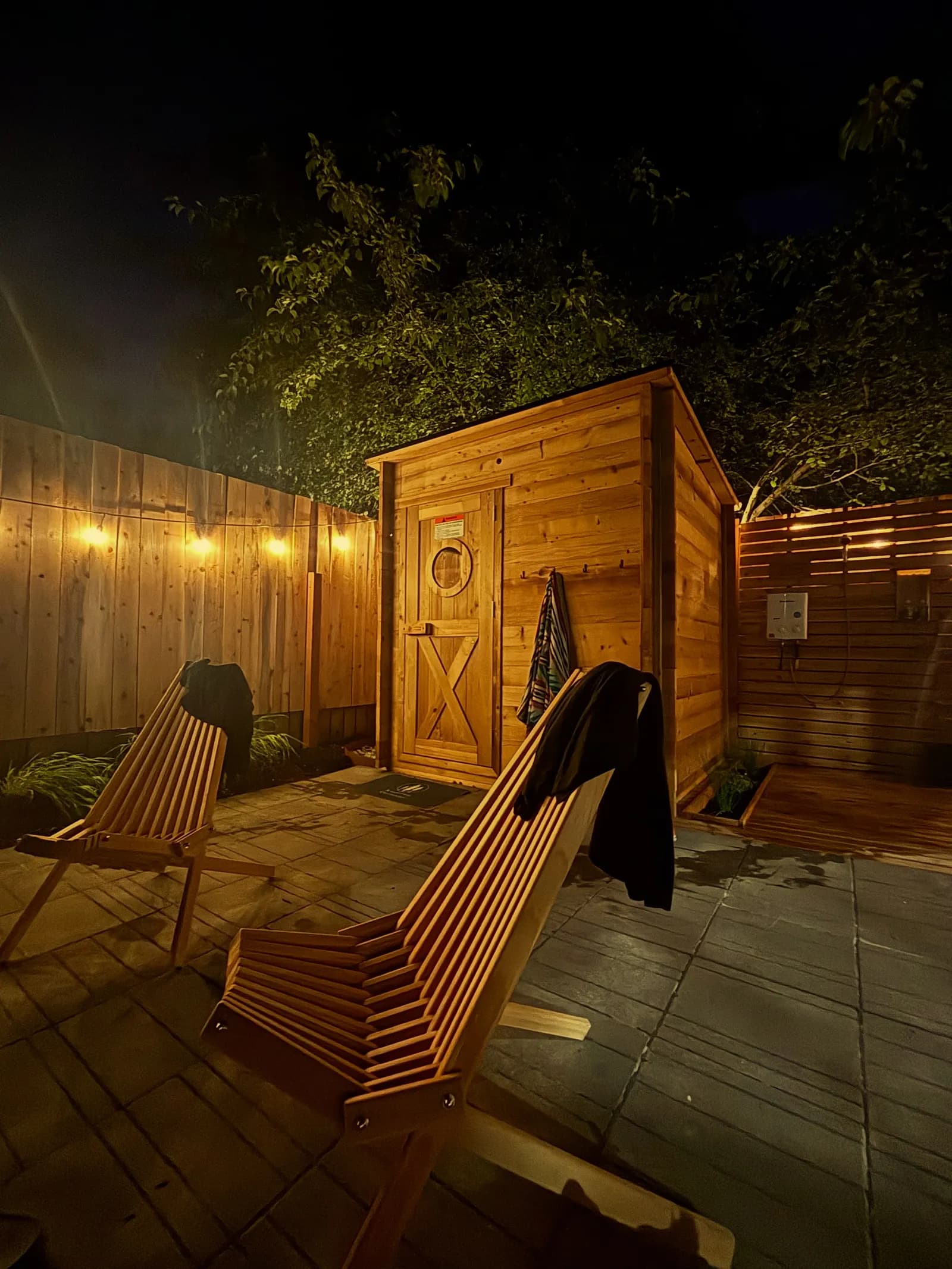 Fern and Thistle backyard sauna at night with string lights