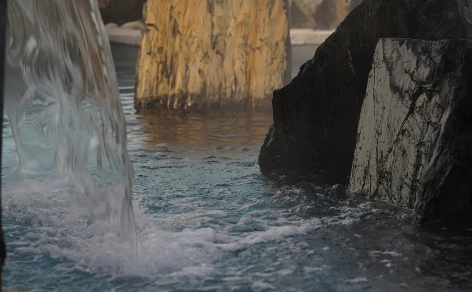 Cold waterfall pouring into a stone-lined pool at Förena Cité thermale