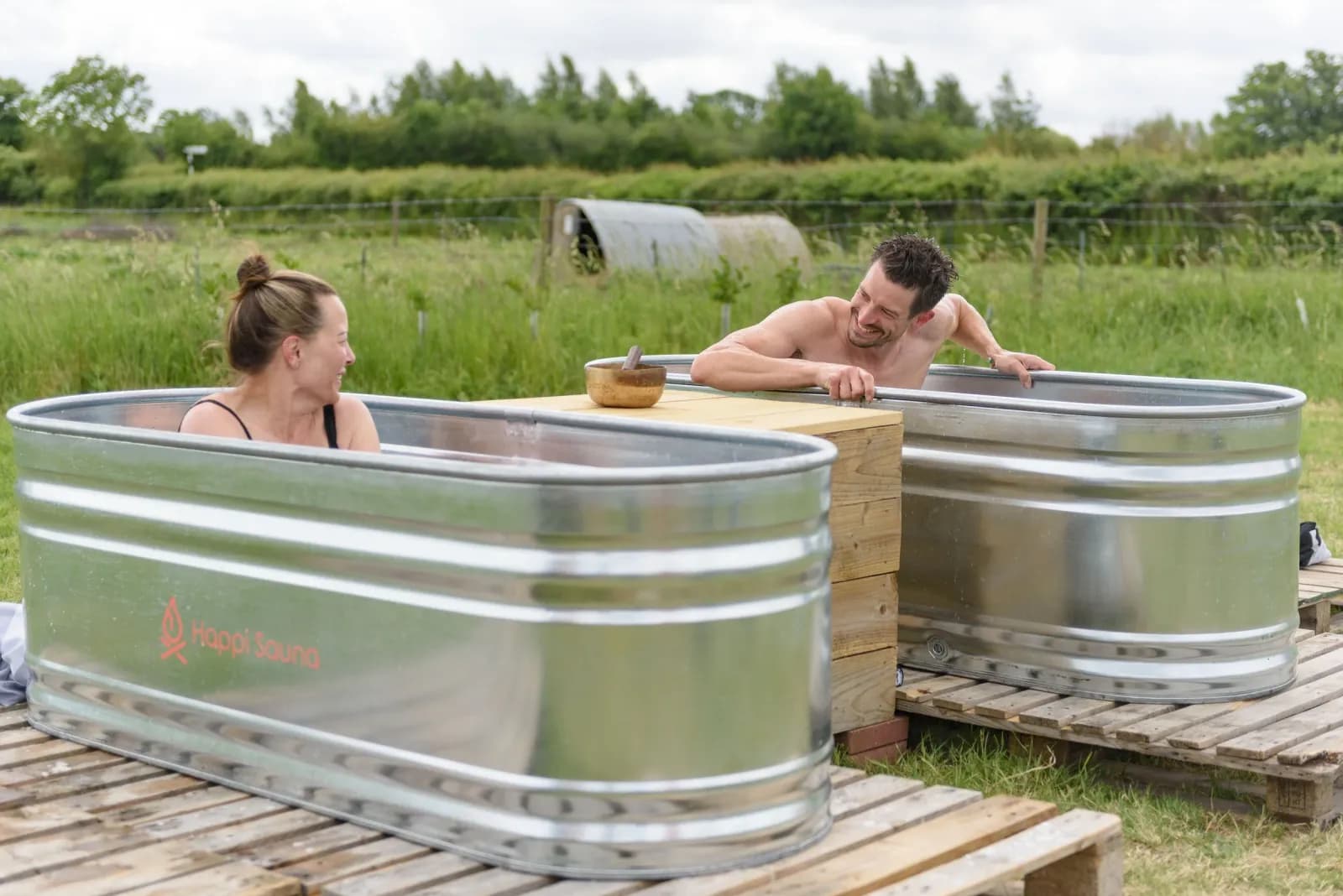Couple relaxing in outdoor cold plunge tubs at Happi Sauna