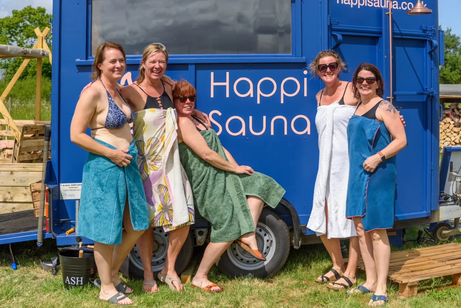 Group of women standing beside the blue Happi Sauna mobile sauna unit