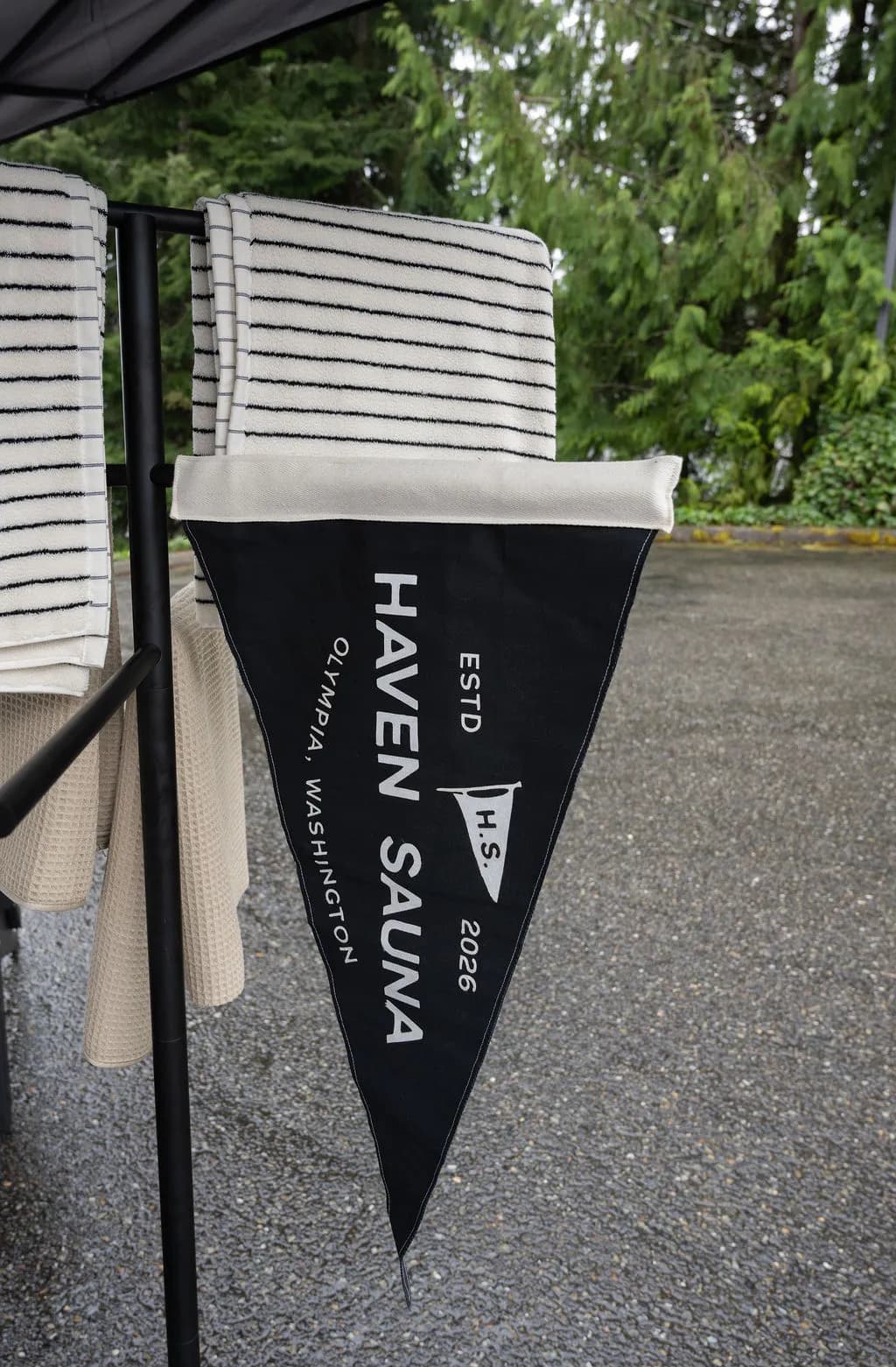 Haven Sauna pennant flag and stacked striped towels at a pop-up sauna station