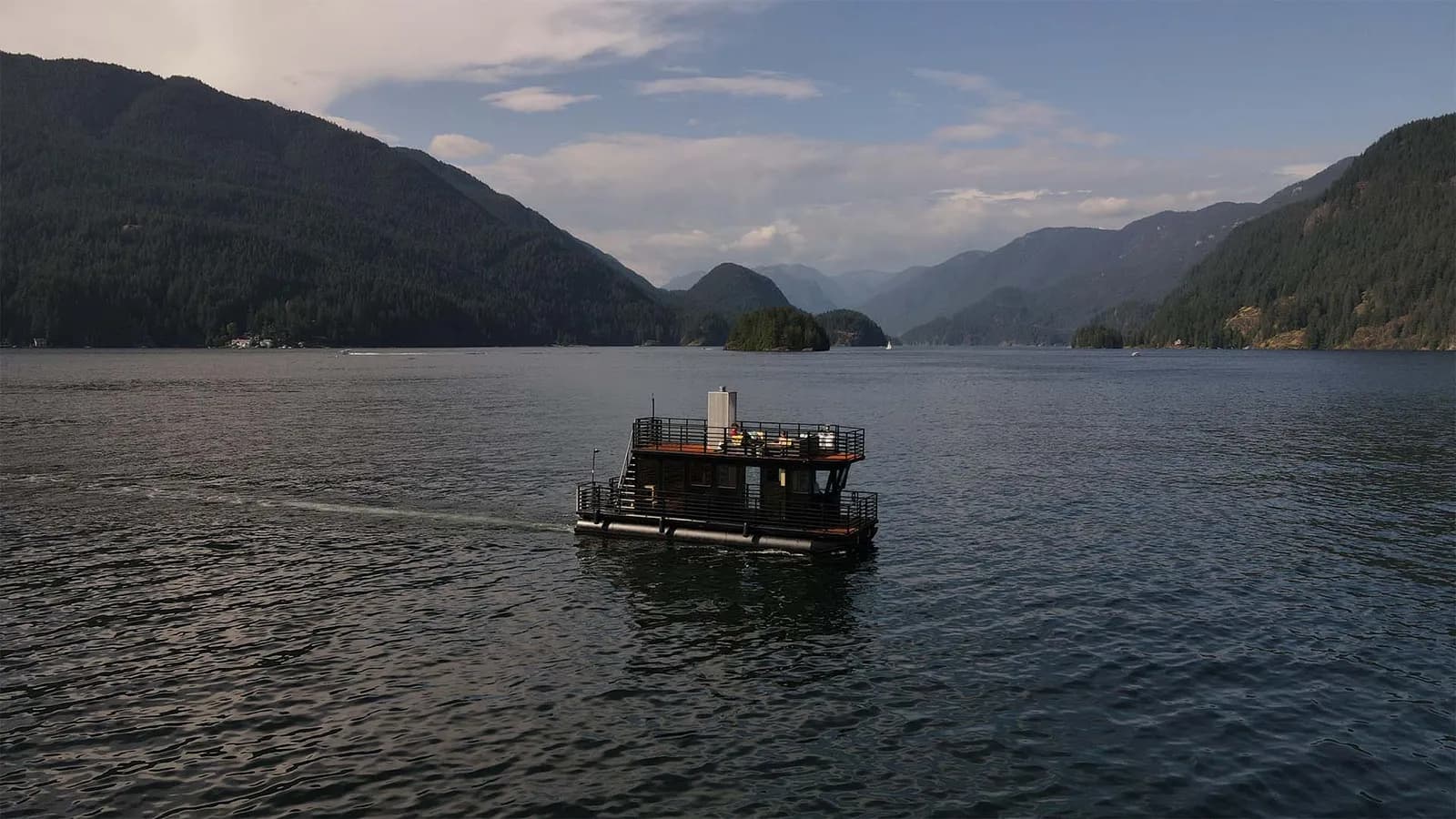 Hot Voyage sauna boat cruising Indian Arm near Deep Cove with forested mountains behind