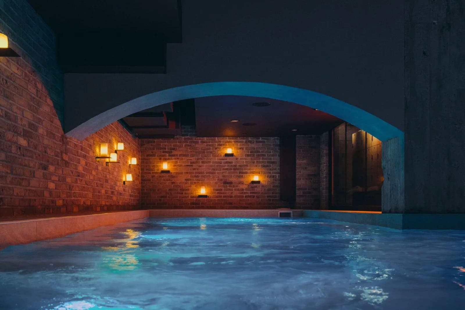 Warm thermal bath under a brick archway at JOY Wellness Club