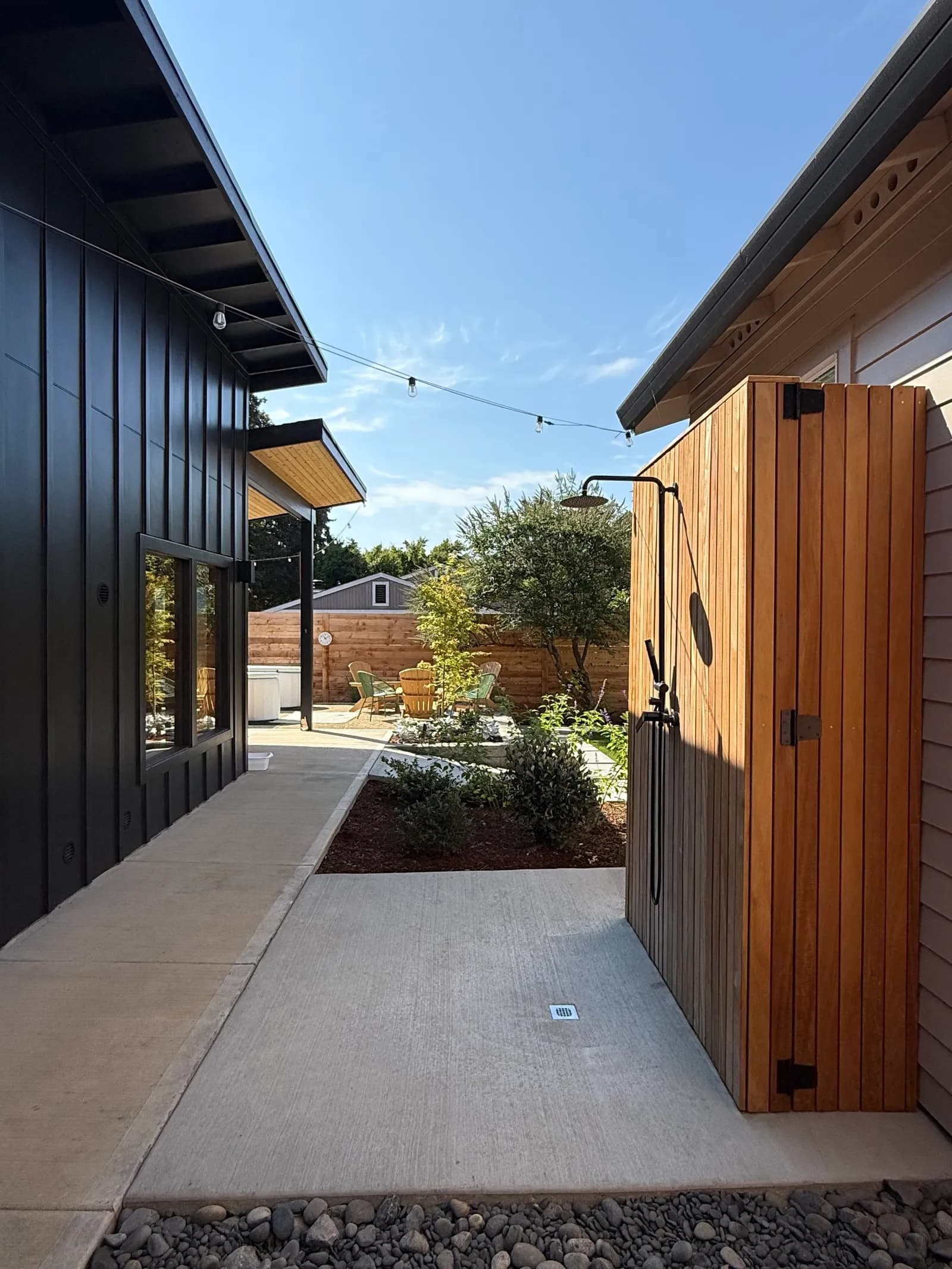 Koti Sauna outdoor walkway with cedar siding and string lights