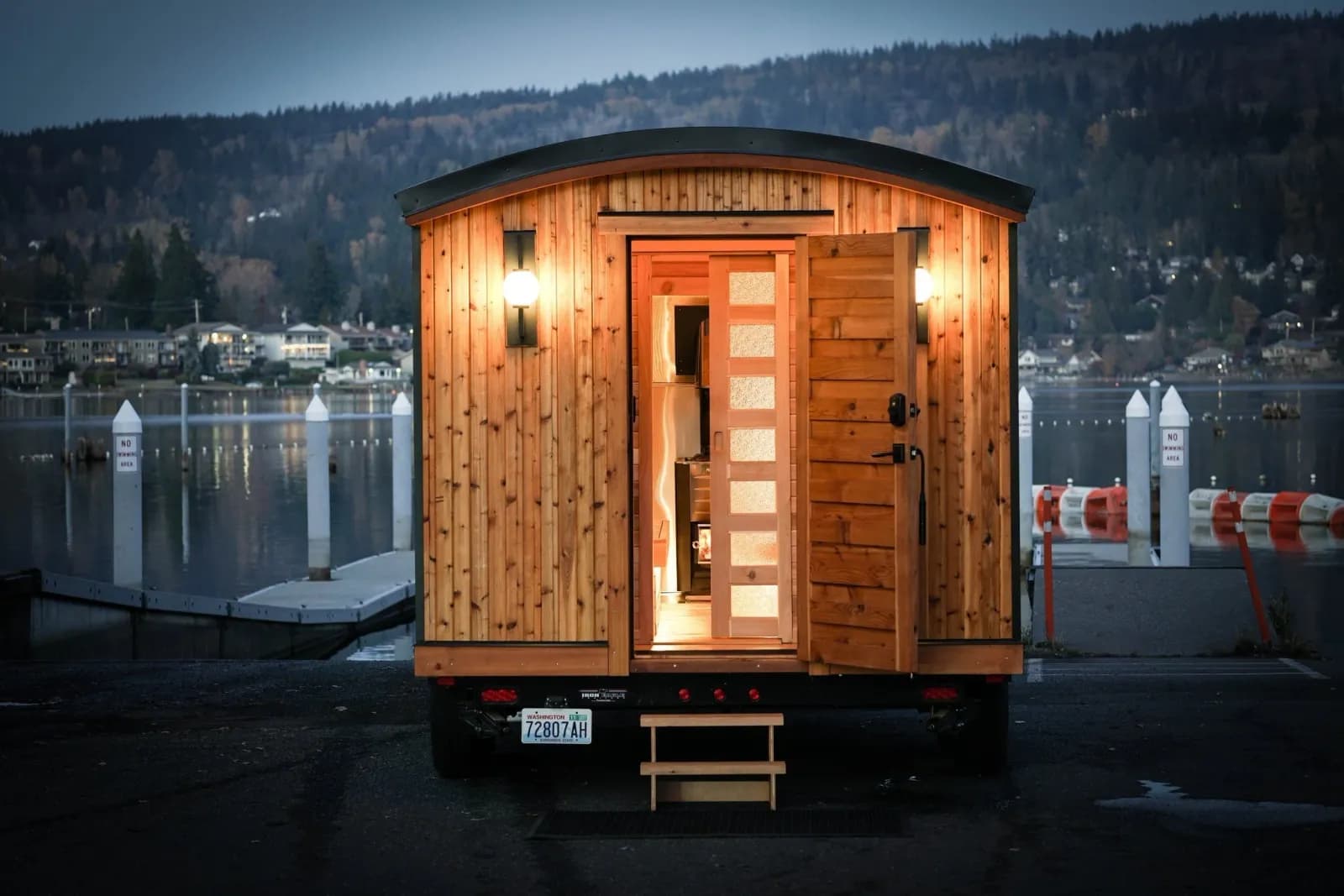 Lemolo Saunas mobile wood-fired sauna on a trailer by the waterfront at dusk in Bellingham