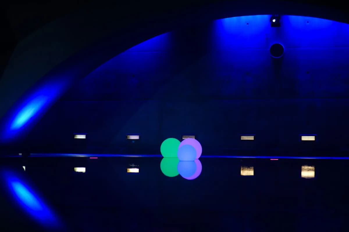 Illuminated floating orbs on the saltwater pool at Liquidrom Berlin under blue dome lighting