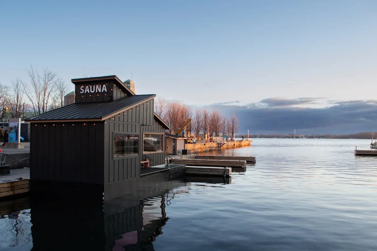 Löyly Floating Sauna on Toronto Harbour at sunset with SAUNA sign illuminated