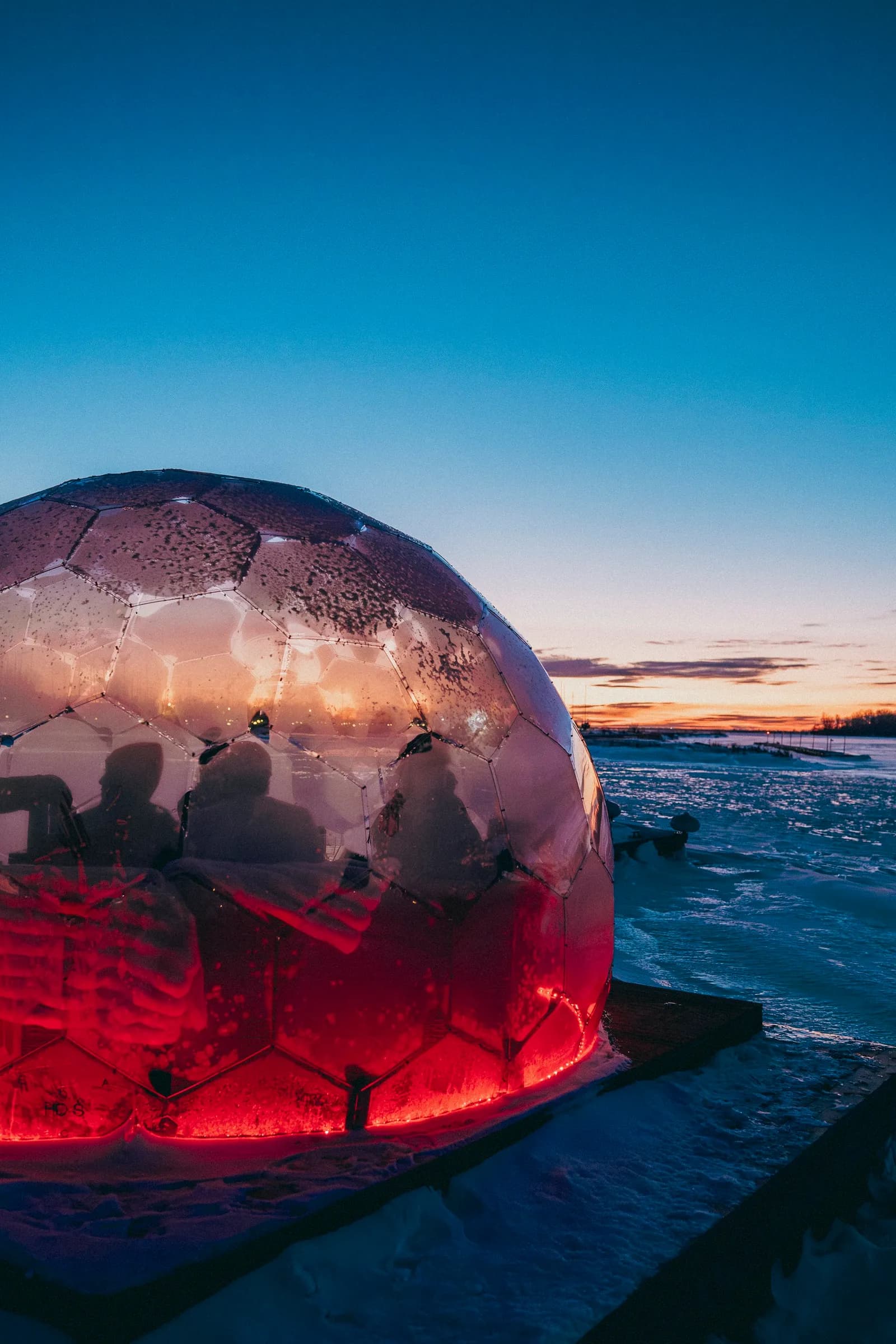 Aerial view of NordiQ's two floating saunas and heated dome on the frozen marina at Valleyfield