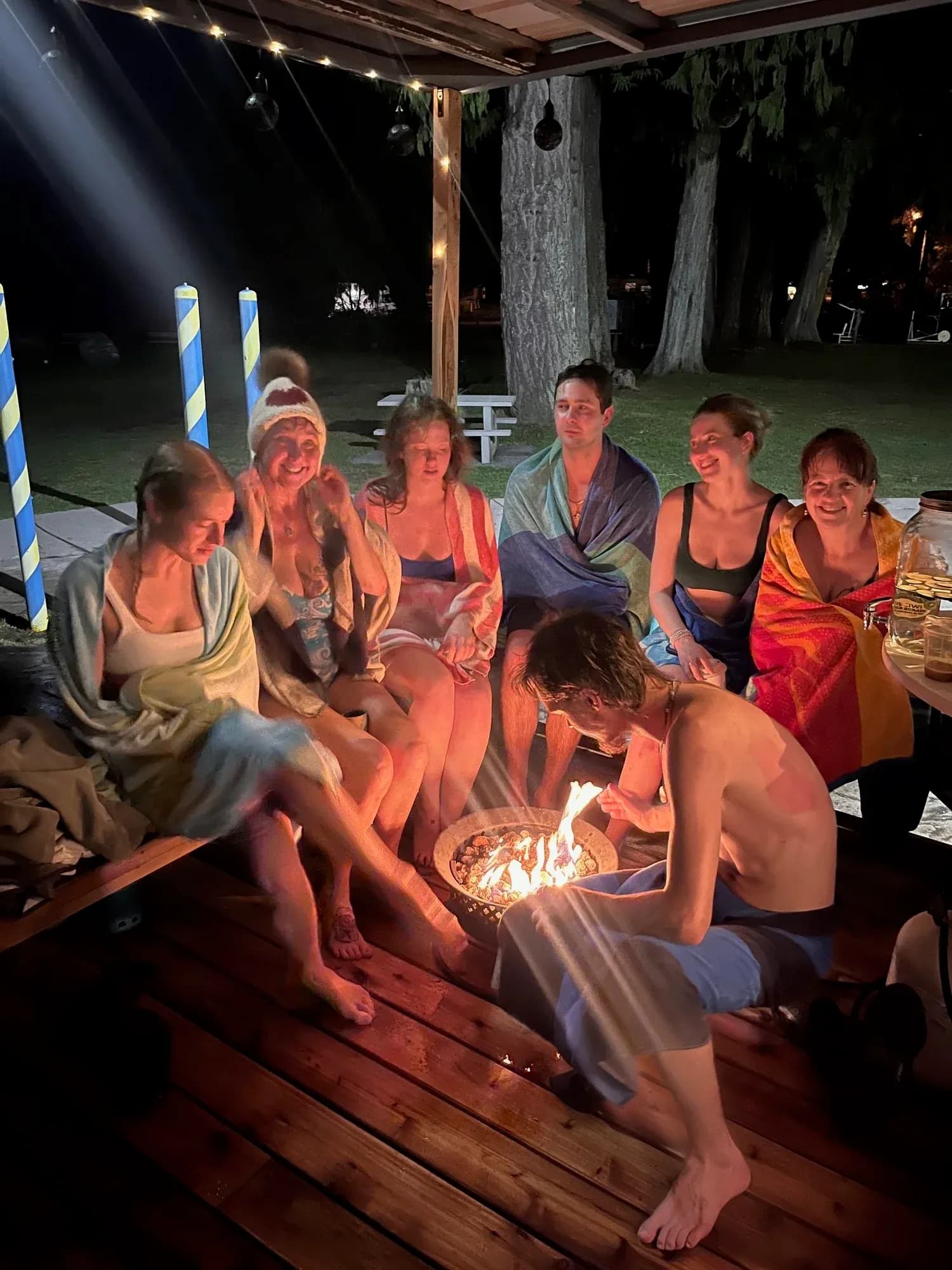 Community gathered around a fire pit at the Orca Saunas oceanside sauna village