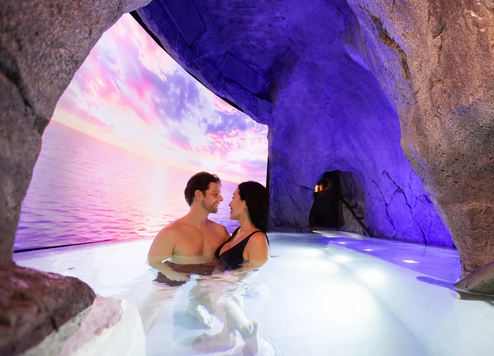 Couple in the Storm Cave hydrotherapy infinity pool with ocean storm projection
