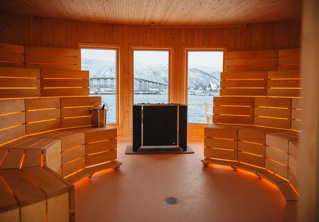 Inside the Lavvo sauna at Pust Tromsø with panoramic harbour views and warm lighting