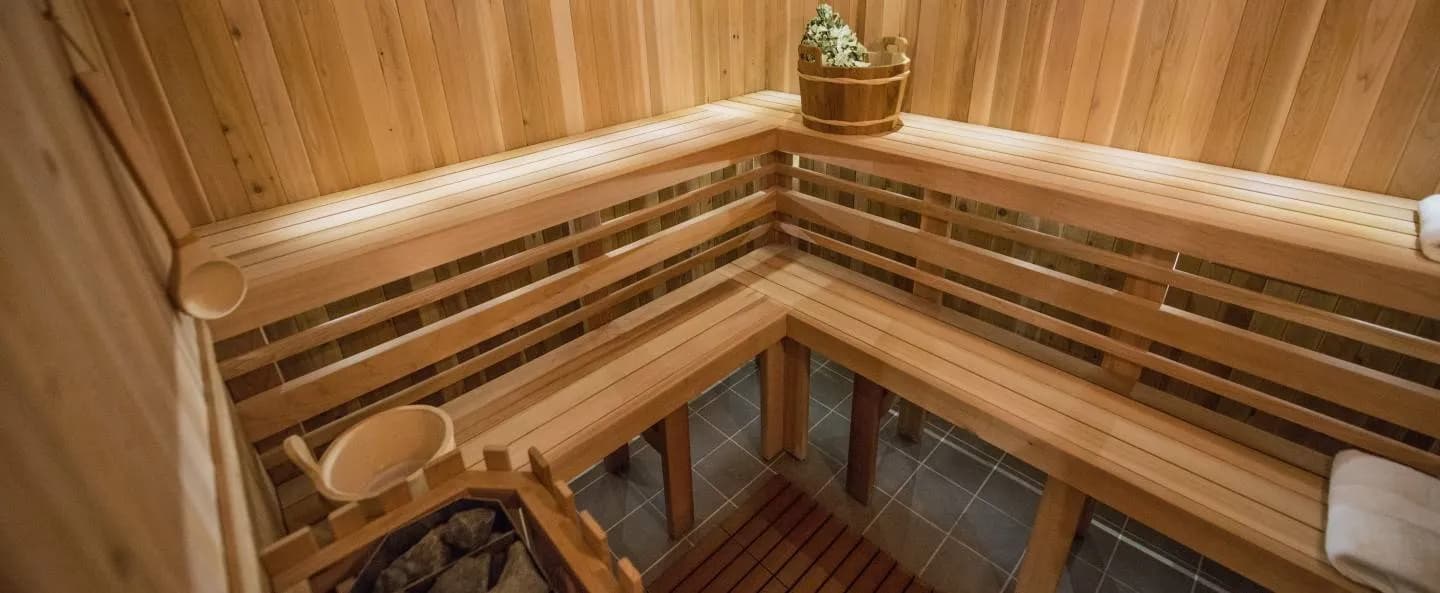 Cedar banya steam room with bench tiers and birch besom bucket