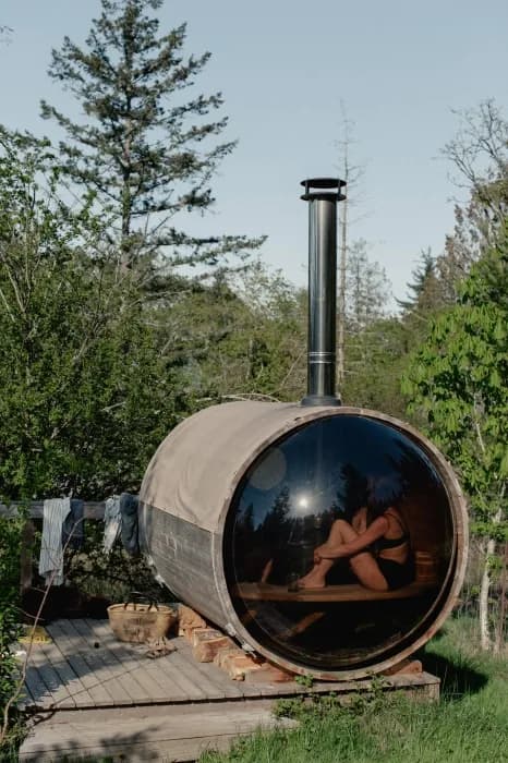 Wood-fired barrel sauna at Salty Pear surrounded by heritage orchard trees on Salt Spring Island