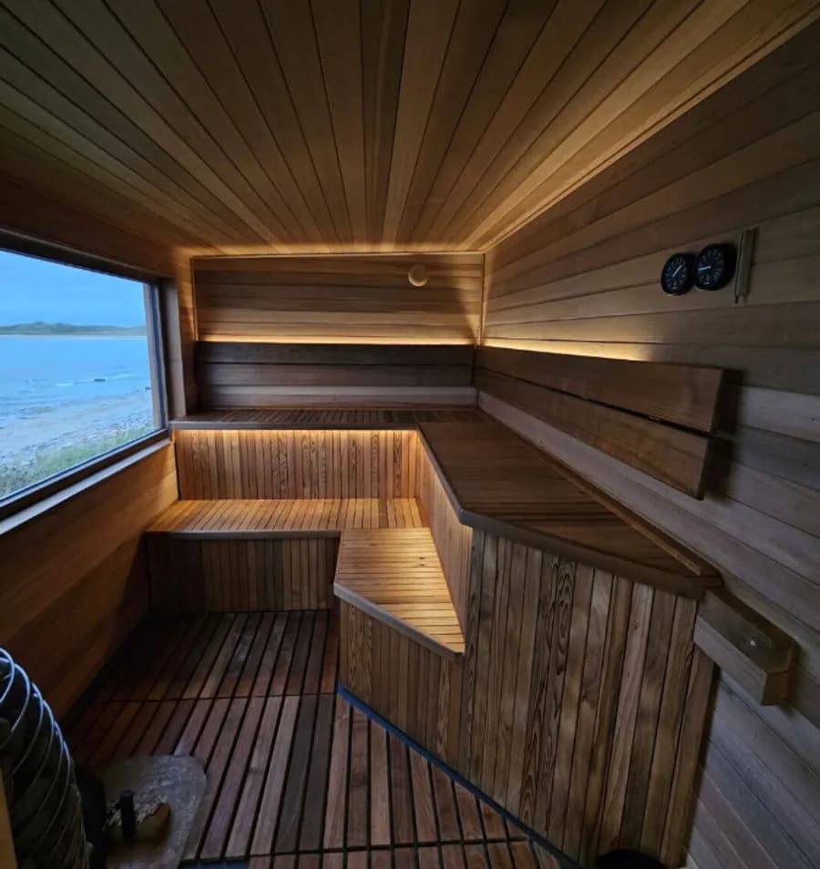 Wood-fired sauna interior with panoramic window overlooking Dunnet Bay