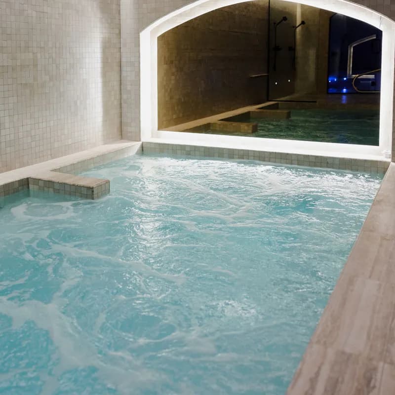 Tiled hot bath with jets under an arched alcove at Spa Carré St-Louis