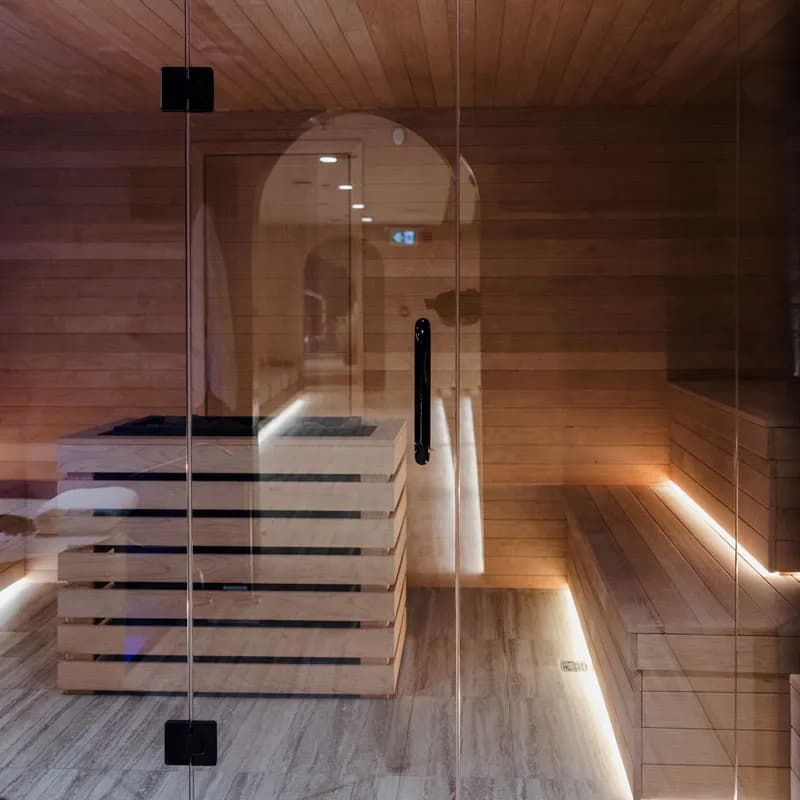 Glass-fronted Finnish sauna with pale wood benches at Spa Carré St-Louis, Montréal