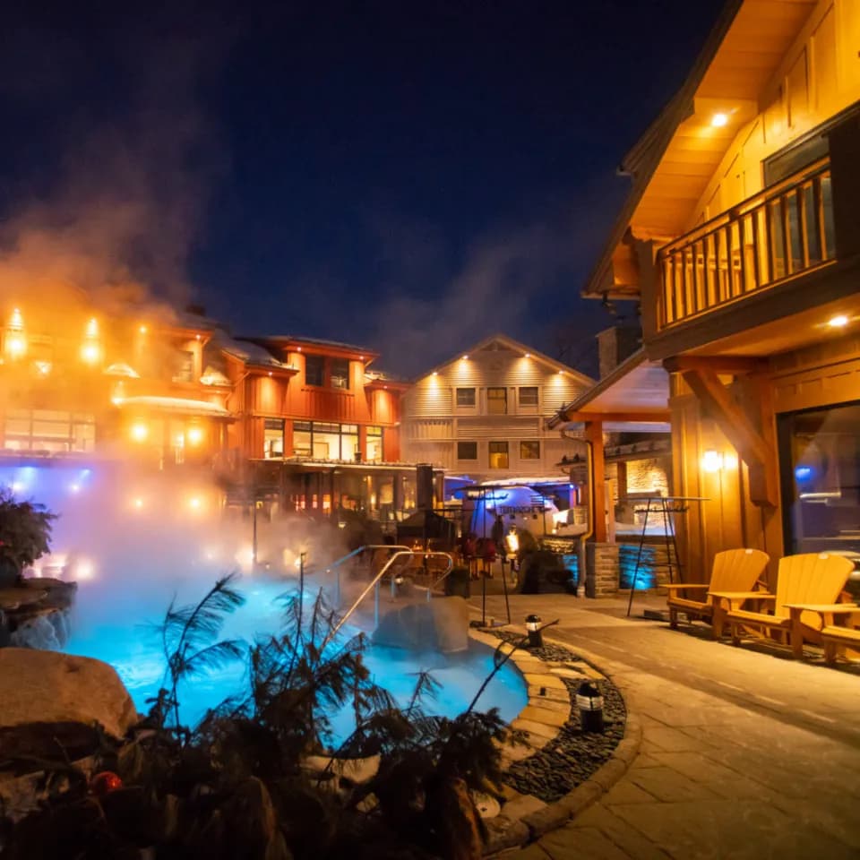 Spa Le Finlandais lodges and steaming illuminated pool at night