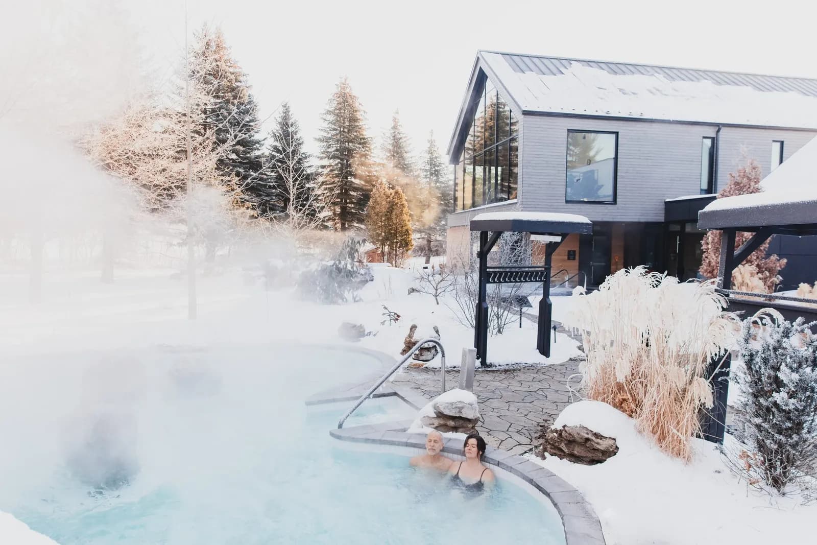 Outdoor baths in winter with steam rising beside the spa pavilions at Strøm Mont-Saint-Hilaire