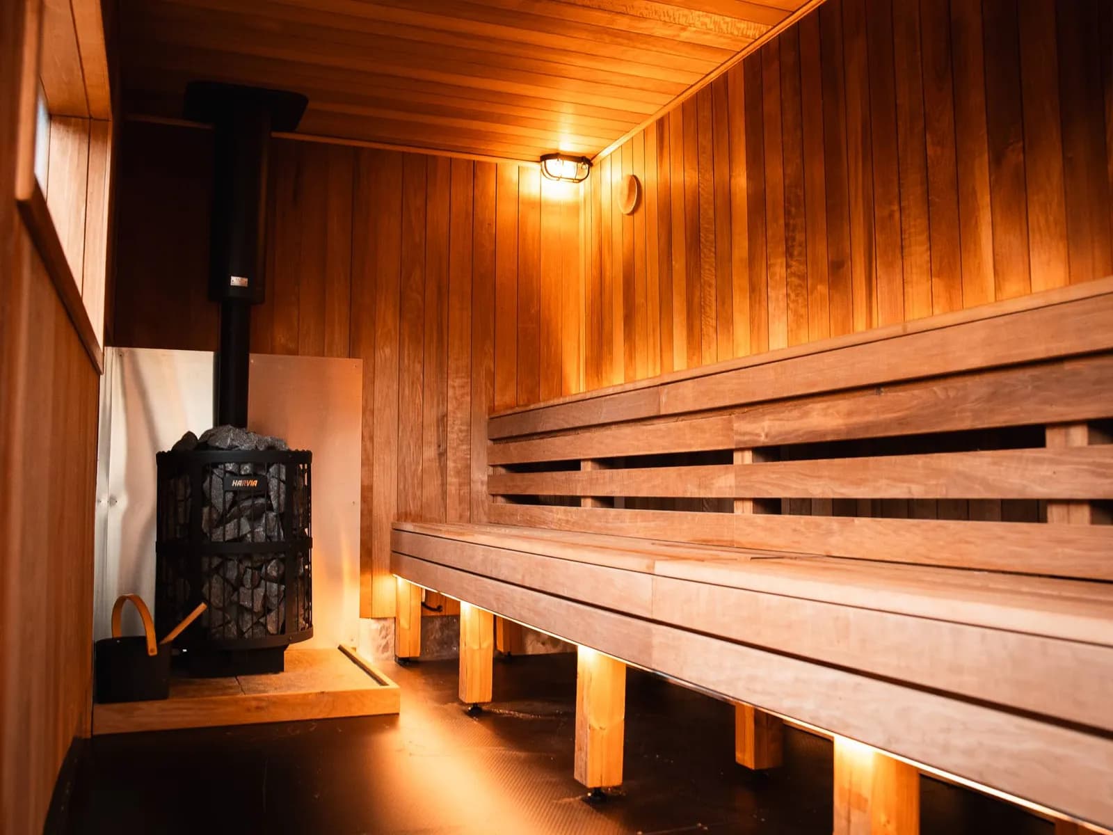 Inside the wood-lined sauna at The Cabin, benches lit warm amber