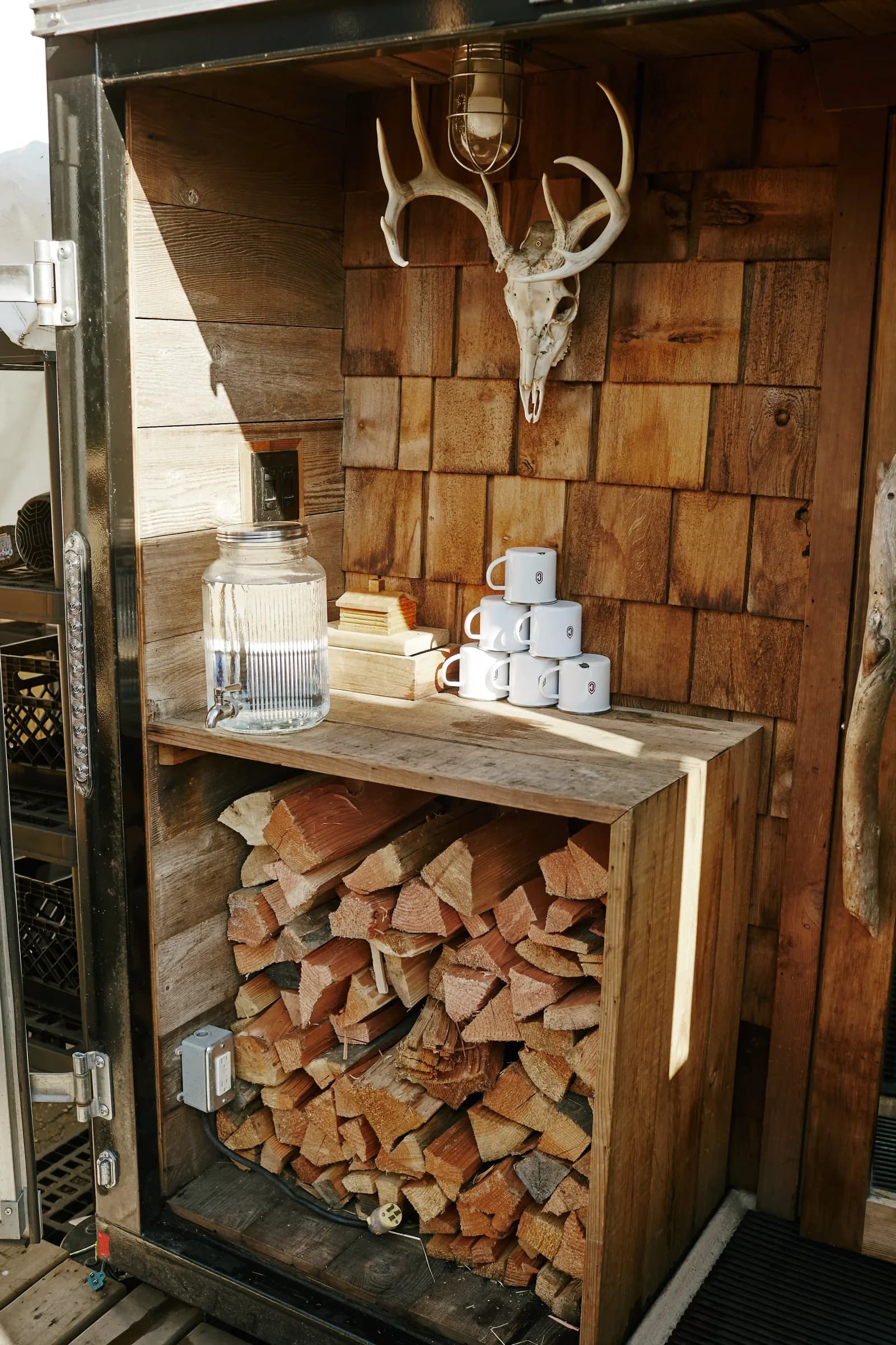The Good Sauna firewood storage and mugs with cedar shingle wall