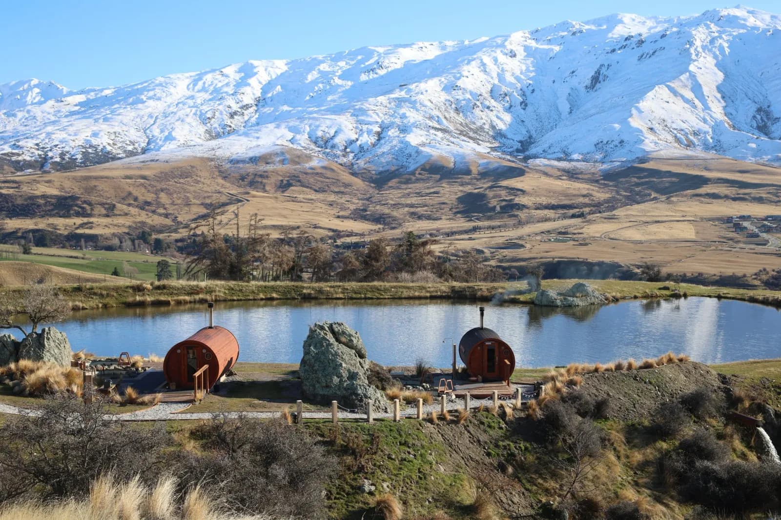 The Secret Sauna Cardrona's barrel saunas and mountain-creek plunge pond framed by the snowy Southern Alps