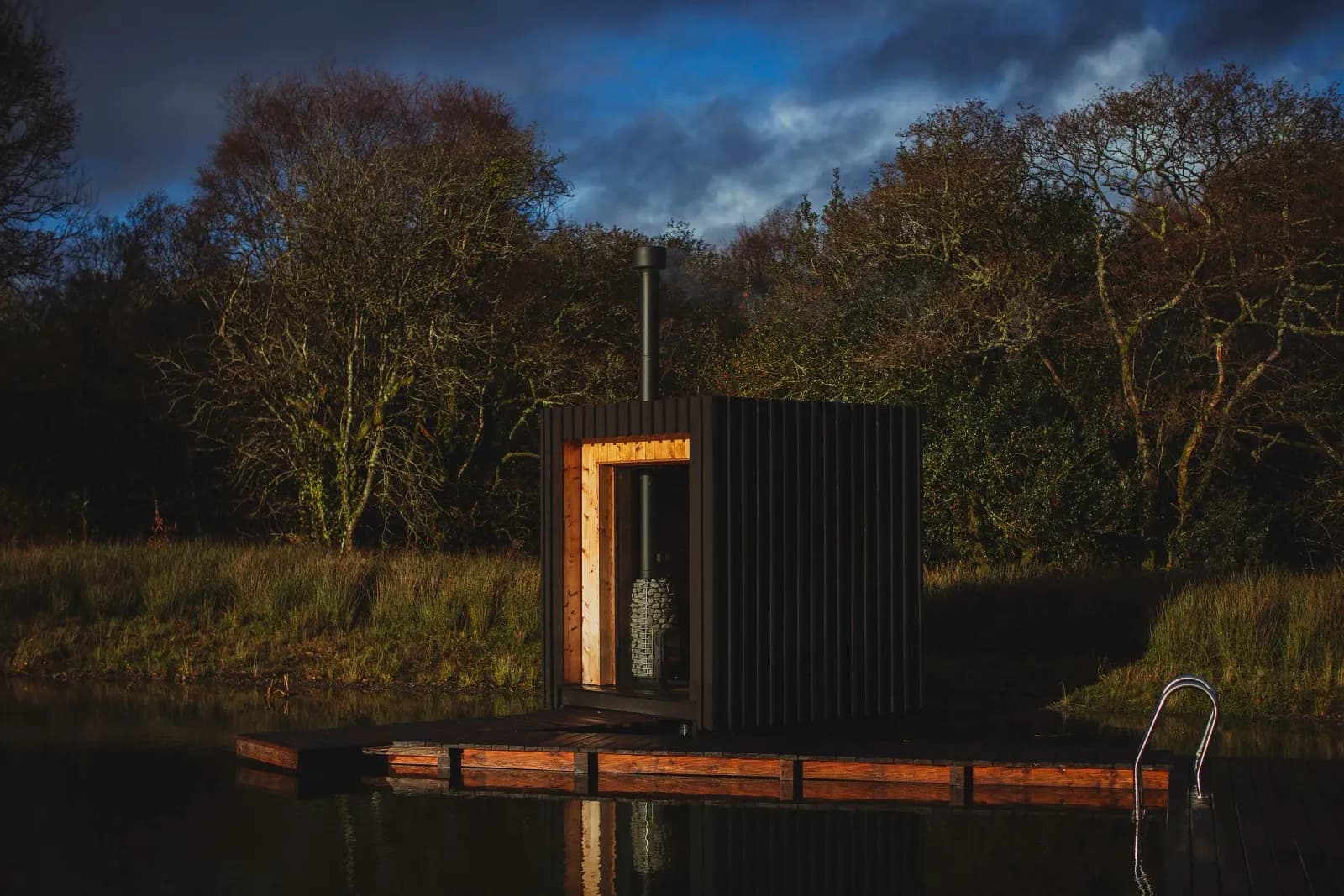 Wood-fired sauna floating on a natural swimming pool at The Wood Stars in West Wales