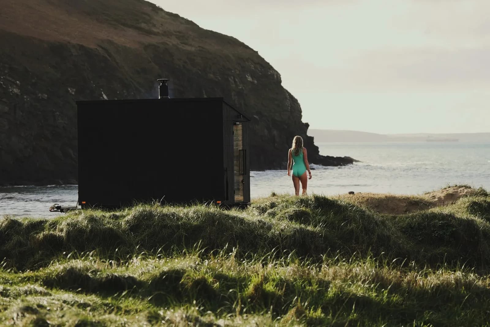 Wildwater Sauna on a clifftop overlooking the Atlantic with a swimmer nearby