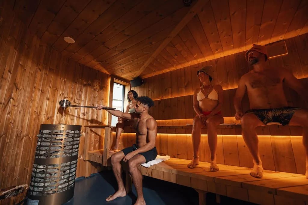 Guest pouring löyly on the electric heater inside the ceremony sauna at Ærth Saunas
