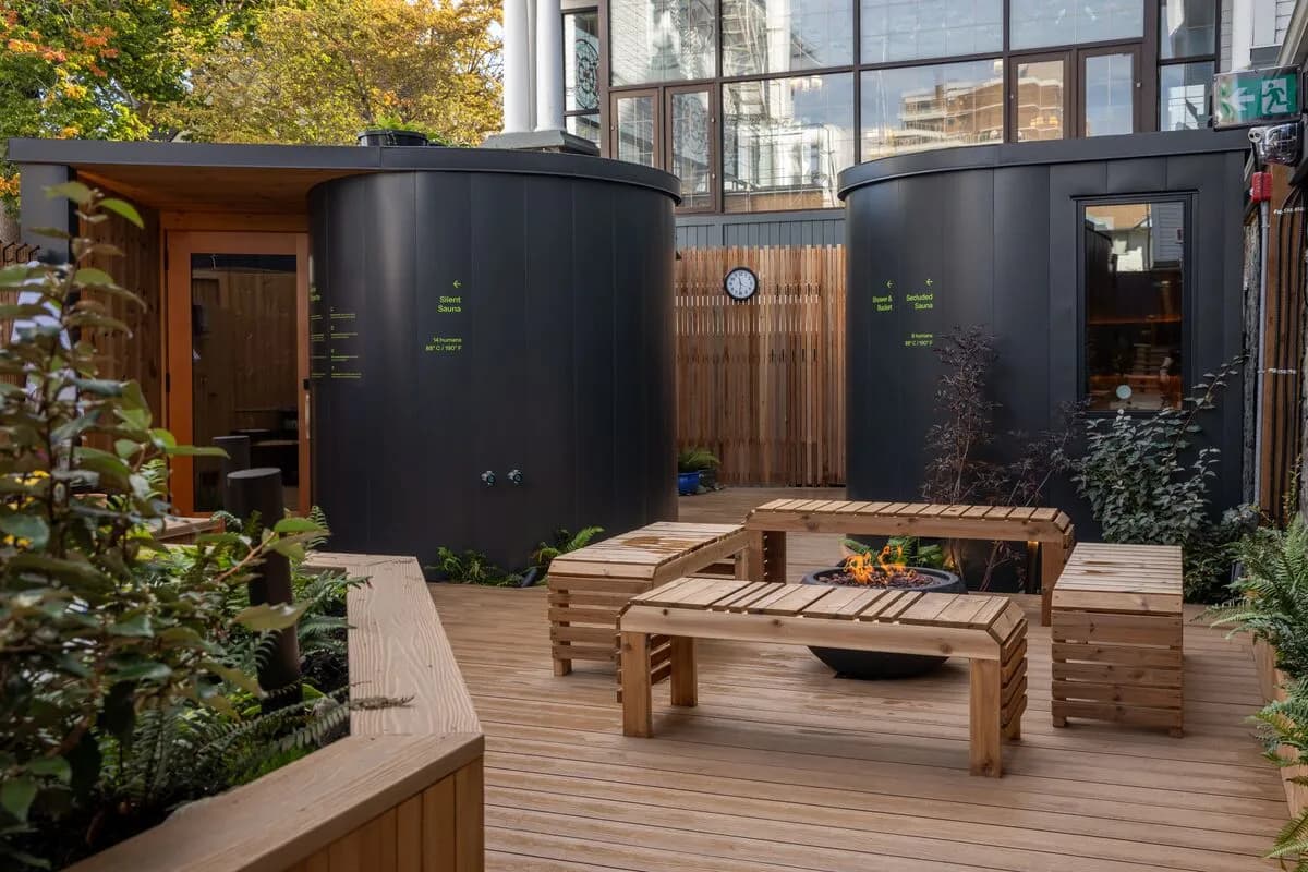 Outdoor courtyard with cylindrical saunas and fire pit at Ærth Saunas in downtown Victoria