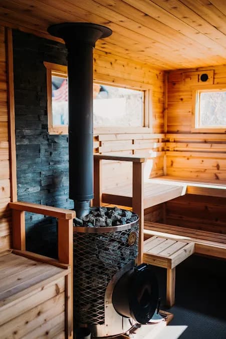 Hearth Sauna downtown interior with wood-fired stove, stone backsplash, and cedar benches