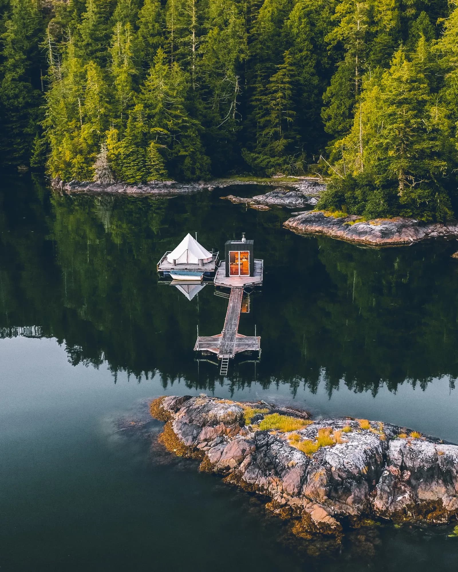 Aerial view of the Lagoon Float Camp floating sauna and bell tent moored in a forested Clayoquot Sound inlet near Tofino