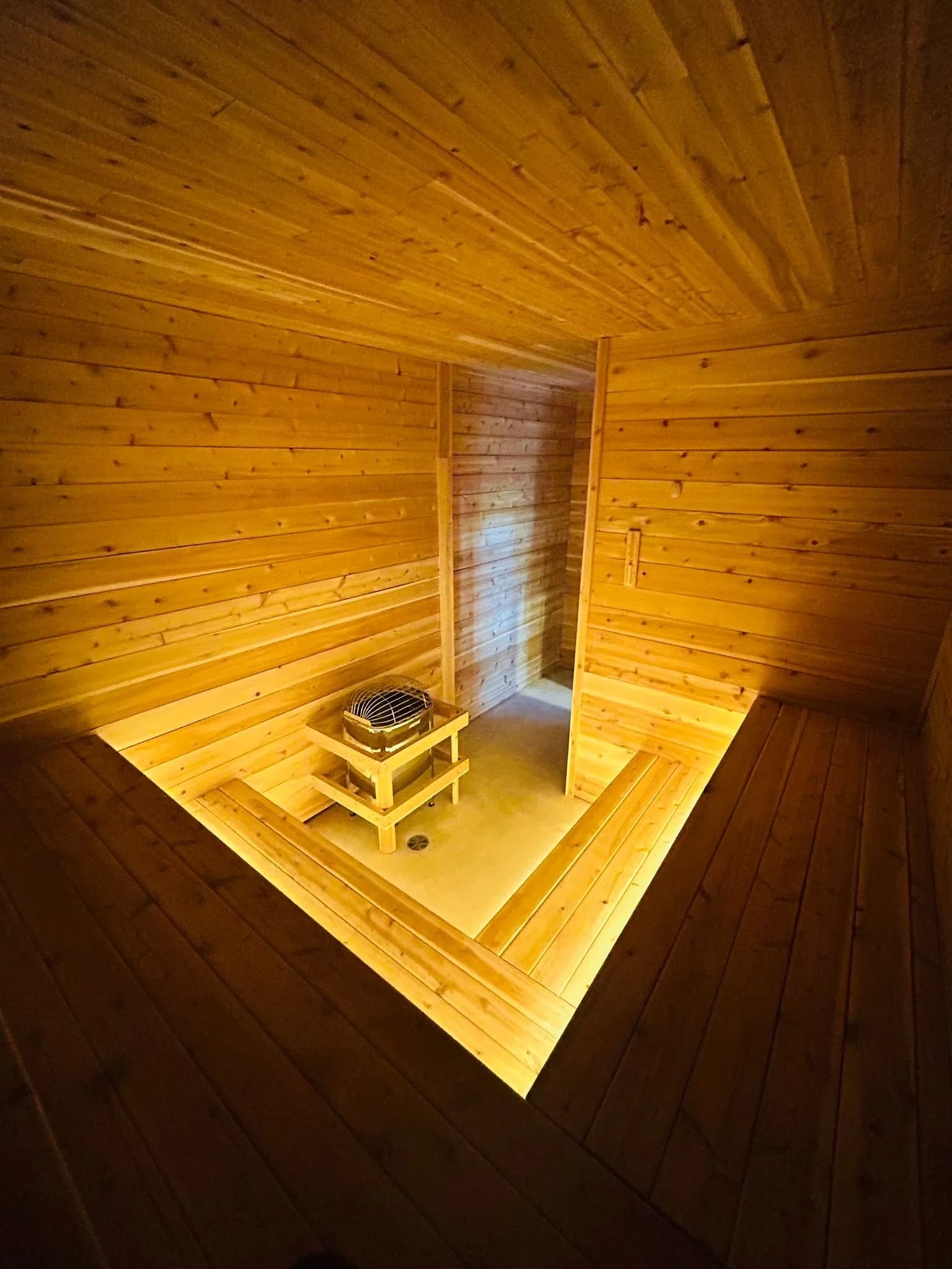 Cedar sauna interior with wood-burning stove at Nordique de la Vie
