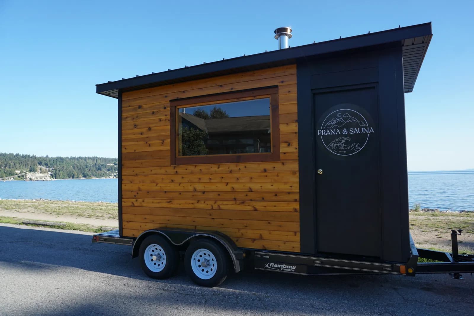 Cedar Prana Sauna trailer parked beachside on the Sunshine Coast with the Salish Sea behind