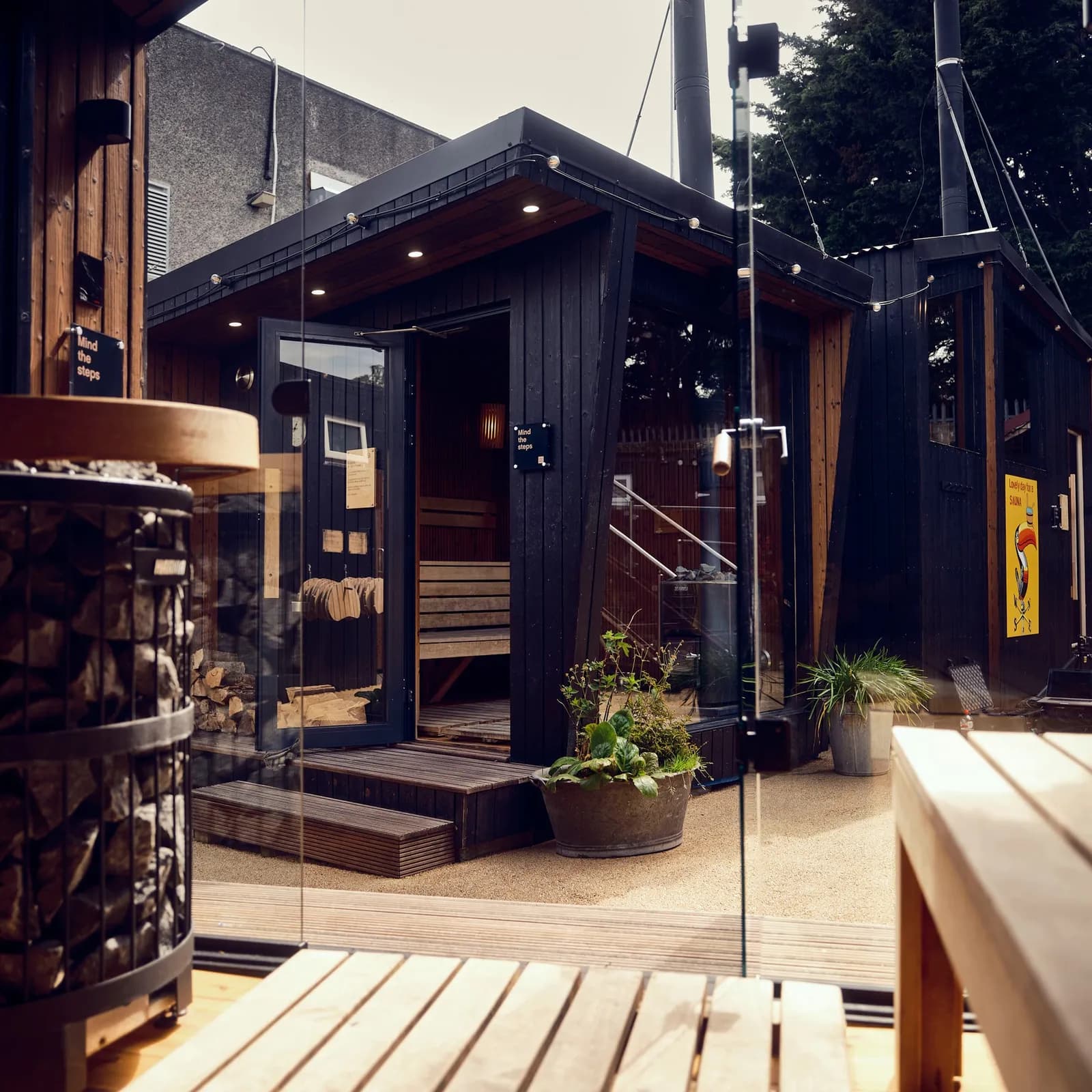 Wood-fired sauna cabin at The Hot Box Sauna Inchicore village with glass-enclosed heater and wooden benches