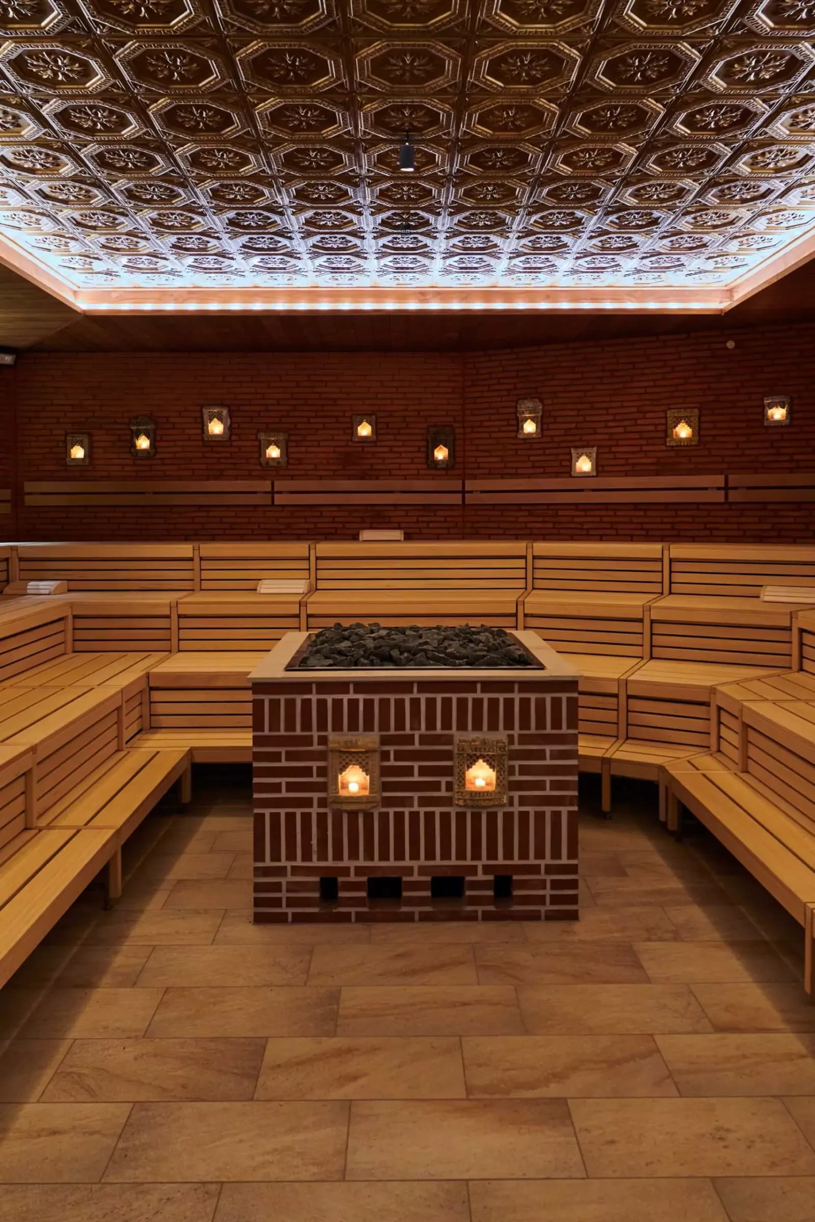 Large sauna room at Vabali Spa Hamburg with central brick heater, wooden benches, and ornate ceiling